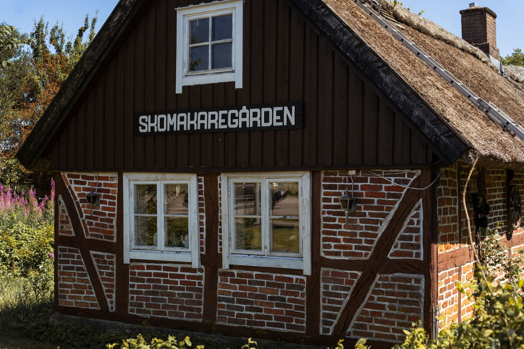 Skomakaregården, ett korsvirkeshus med halmtak och skylt med gårdens namn på gaveln